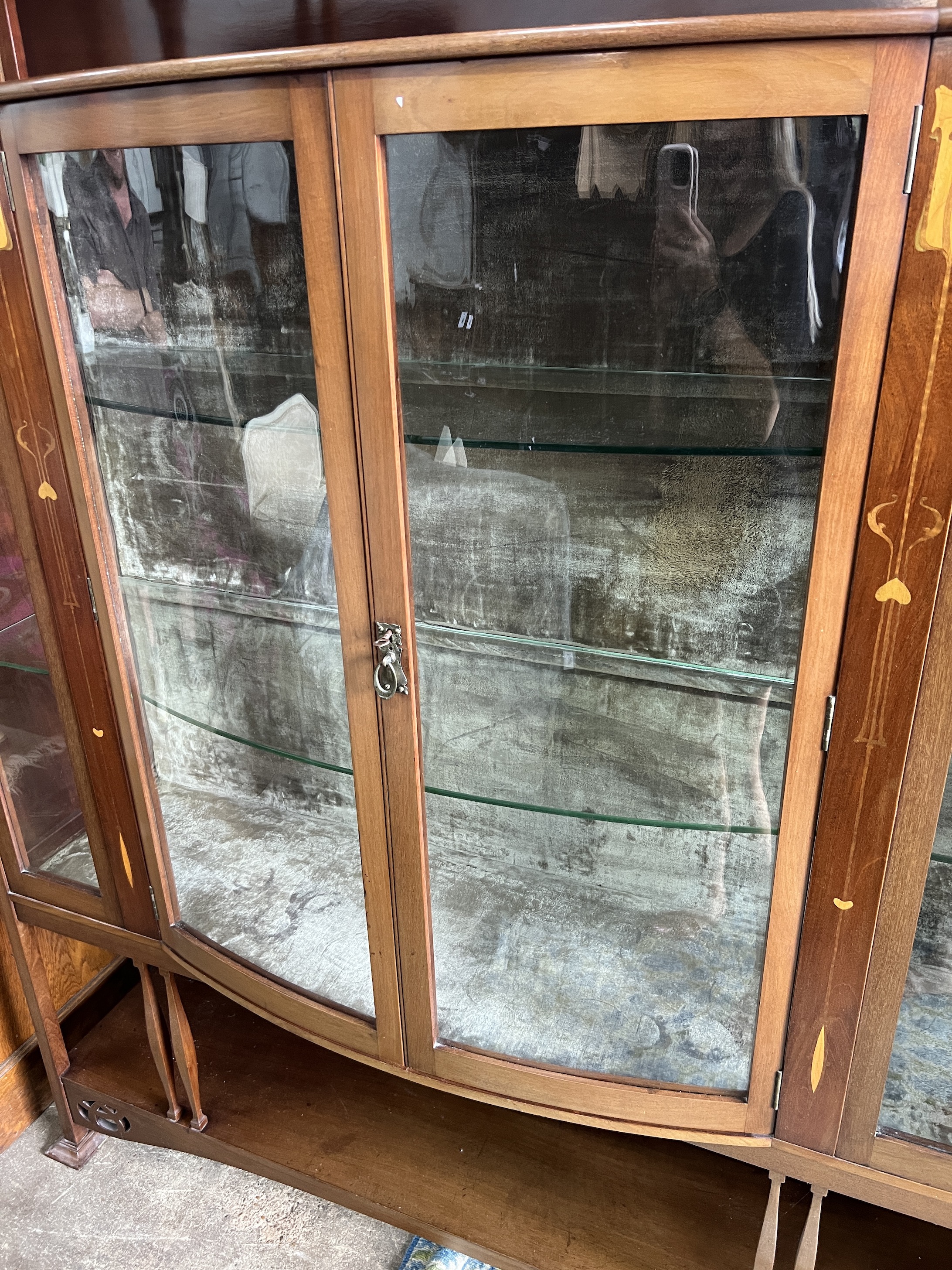 An Arts & Crafts marquetry inlaid mahogany bowfront display cabinet, width 157cm, depth 38cm, height 183cm